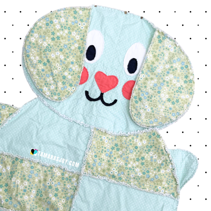 Quilted dog rage quilt with floral patterns on a white background