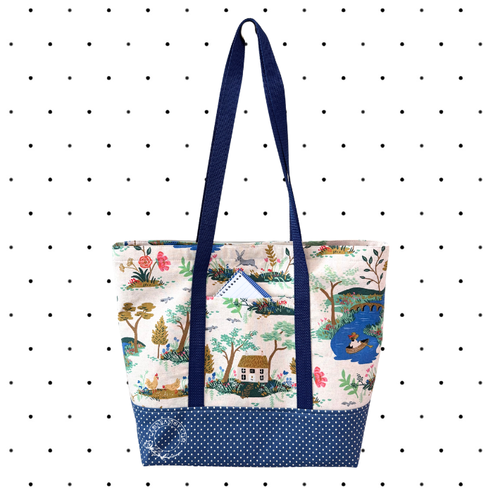 Tote bag with nature-themed design and blue handles on a polka dot background