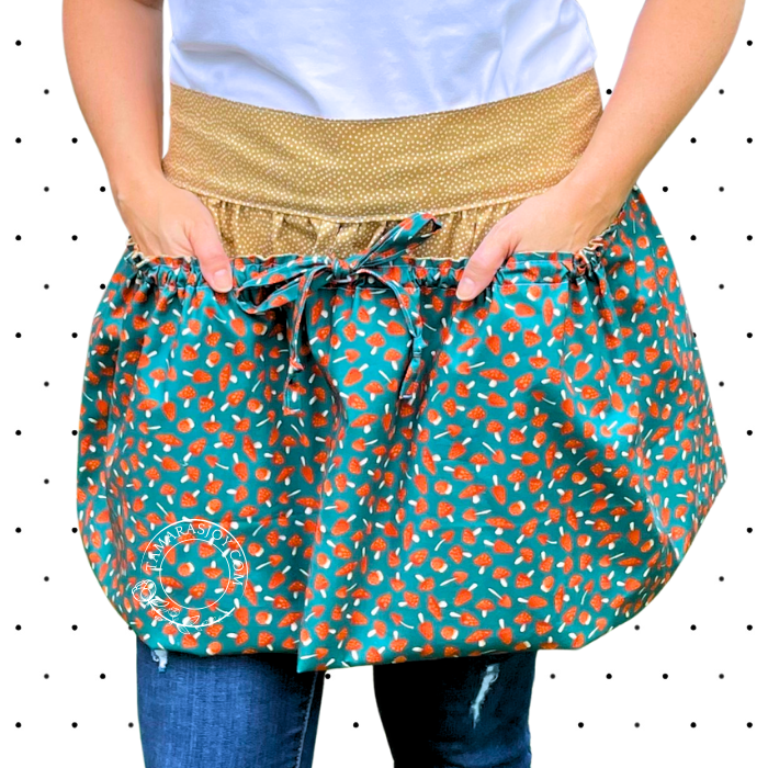 Person wearing a teal apron with orange patterns and a gold waistband.